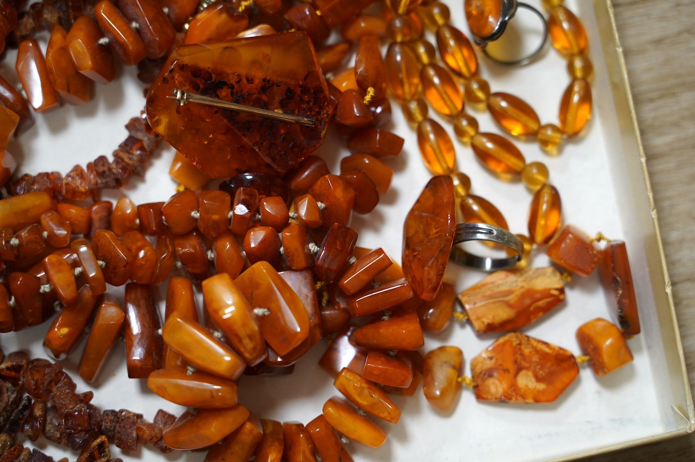 Five assorted single strand amber necklaces, including jagged pebble and unpolished, longest 176cm, together with two mounted amber rings, a pair of ear clips and a brooch, gross weight 357 grams. Condition - poor to fai